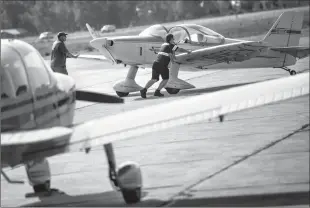  ?? Herald photo by Ian Martens @IMartensHe­rald ?? A pilot and airfield staff move a plane into position outside of the Airwest hanger after landing Friday morning at the Lethbridge Airport.