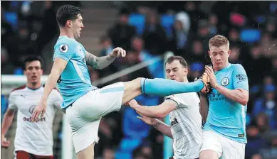  ?? PHIL NOBLE / REUTERS ?? Manchester City defender John Stones miscues to almost connect with teammate Kevin De Bruyne’s face during City’s 3-0 English Premier League victory over Burnley at Etihad Stadium in Manchester on Saturday.