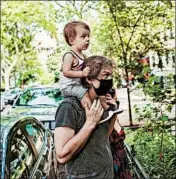  ?? ARMANDO L. SANCHEZ/CHICAGO TRIBUNE PHOTOS ?? Ben Haley holds up his 2-year-old son Sebron while watching Matthew Owens perform a puppet show for neighbors from the balcony of his home in Lakeview on June 21.