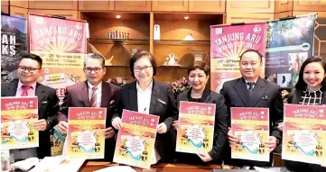  ??  ?? From second left, Datu Rosmadi, Christina, Suzaini and others showing posters of the Tanjung Aru Beach Festival.