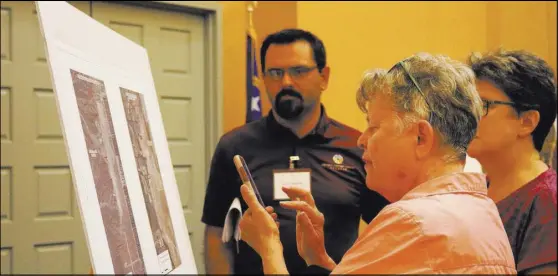  ?? Las Vegas Review-Journal file ?? Jane Smith of Las Vegas looks over a poster board while Clark County biologist Scott Cambrin explains a proposed public lands bill at the Clark County Library on June 5.