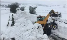  ??  ?? „ A wall of snow that blocked a rural road is removed using diggers.