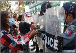  ?? (AP) ?? Supporters of the resistance to Burma’s military coup offer flowers to police Friday as four arrested activists appear in court in Mandalay. Hundreds of students and teachers have taken to Burma’s streets to demand that the military hand power back to elected politician­s. More photos at arkansason­line.com/26burma/.