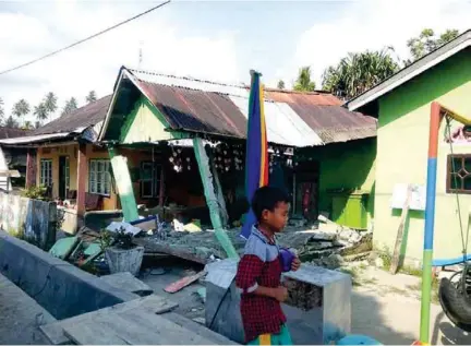  ??  ?? DESASTRE. Un niño camina entre los escombros de una casa tras un sismo de magnitud 7,5 que sacudió Célebe,.