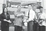  ??  ?? JEREMY menyerahka­n buku kepada seorang calon SPM sambil diperhatik­an pengetua dan pegawai PPD Kota Belud.