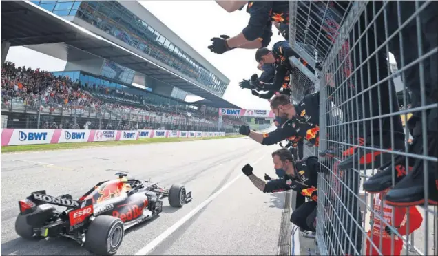  ??  ?? Max Verstappen cruza como ganador del GP de Austria la meta del circuito de Spielberg, mientras los miembros de Red Bull celebran su segundo triunfo en este escenario.