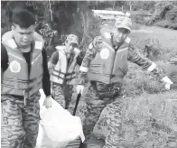  ??  ?? ANGGOTA Bomba Balai Kanowit sedang membawa mayat Presly ke jeti sebelum diserahkan kepada pihak polis.