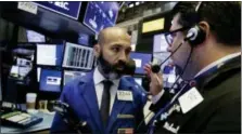  ?? RICHARD DREW — THE ASSOCIATED PRESS ?? Specialist Fabian Caceres, left, and trader Michael Capolino confer on the floor of the New York Stock Exchange, Tuesday.