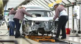  ?? STAFF PHOTO BY ERIN O. SMITH ?? Volkswagen employees work around a car on the assembly line at the production plant in Chattanoog­a. VW employs about 3,500 people in the city.