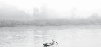  ??  ?? A man rows a boat along the Baram River in Marudi on Tuesday during hazy conditions.