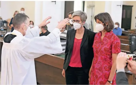  ?? FOTO: FELIX HÖRHAGER/DPA ?? Pfarrvikar Wolfgang Rothe segnet Christine Walter und Almut Münster (r.) bei einem Gottesdien­st in der Münchner Kirche St. Benedikt.