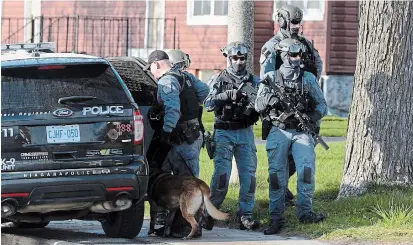 ?? DAVE JOHNSON TORSTAR ?? Members of the Niagara Regional Police emergency task unit and a canine unit walk down King Street in Welland Friday afternoon as they search for a man wanted for kidnapping people and forcing them to withdraw money from banks.