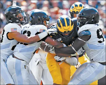  ?? PAUL SANCYA/AP ?? Army defenders stop Michigan running back Zach Charbonnet in the second half Saturday. Michigan won 24-21 in double overtime.