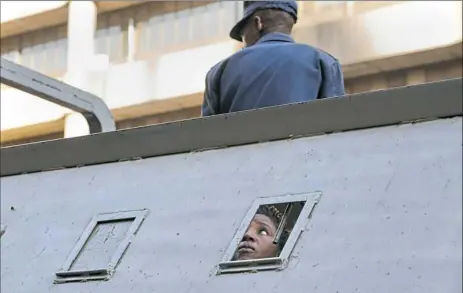  ?? Jerome Delay/Associated Press ?? A supporter of Zimbabwean’s main opposition party is detained in a police vehicle Thursday in Harare, Zimbabwe. Gunfire, tear gas, and burning cars disrupted the city’s streets as armed riot police and army troops clashed with rock-throwing opposition supporters.