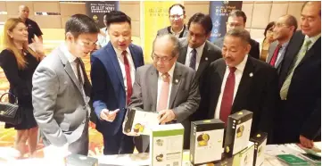  ??  ?? Uggah (centre) looking at one of the durian paste products prior to the signing of the MoU at a leading hotel yesterday. Also seen is Sagah (second right).