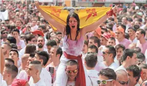  ?? CESAR MANSO, AFP/GETTY IMAGES ?? A woman holds up a flag Thursday as she celebrates the “Chupinazo,” which marks the beginning of the San Fermin Festival in Pamplona, northern Spain. Revelers soak each other with wine to kick off one of Spain’s most famous events, the Running of the...