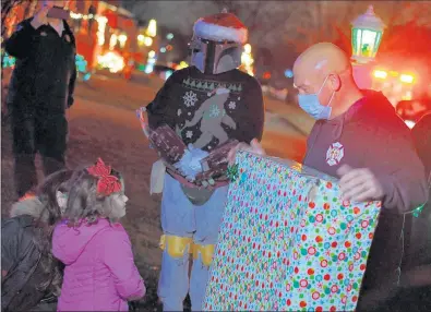  ?? BILL JONES/DAILY SOUTHTOWN PHOTOS ?? Kurt DeGroot talks to Tinlee, of Oak Forest, while bringing her one of many gifts she received from the organizati­on onWednesda­y.