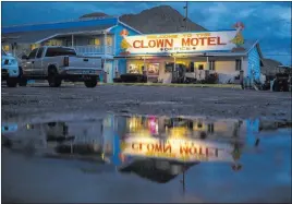  ??  ?? The office of the Clown Motel is reflected in a puddle at dusk in Tonopah on July 25. The motel is for sale with the condition that the new owner must keep the clown theme.