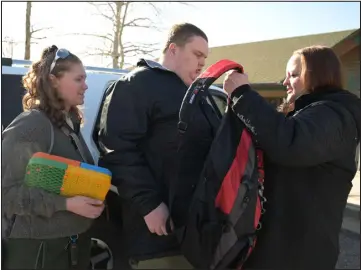  ?? ?? Sabrina Ortengren, right, hands a backpack to son Ethan while dropping him off for the day with Kearns in the parking of Seven Dimensions.