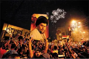  ?? AP/HADI MIZBAN ?? Muqtada al-Sadr carry his image in Baghdad’s Tahrir Square as they celebrate partial election returns Monday.