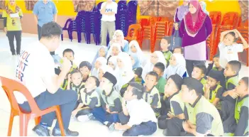  ??  ?? A volunteer reading to the students of SK Bandar Tawau.