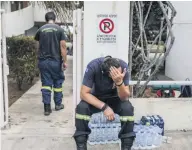  ??  ?? EXHAUSTED Firefighte­r takes break at wrecked village