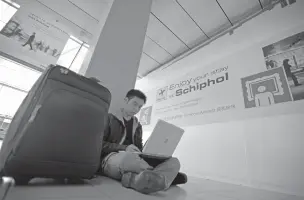 ??  ?? A traveler from Malaysia uses his laptop computer in April 2010 at Schiphol Airport in Amsterdam, Netherland­s. U.S. aviation-security officials appear determined to ban large electronic devices in the cabin of flights from Europe.