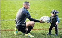  ?? PHOTO: GETTY IMAGES ?? Passing the baton . . . All Black halfback Aaron Smith hands a ball to a child during the captain’s run at Eden Park in Auckland yesterday.