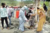  ?? PIC/PTI ?? A worker wearing a protective suit sprays disinfecta­nt on the feet of a migrant leaving for Rajasthan from Vasai Creek, off the national highway in Mumbai, on Thursday