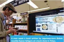  ??  ?? A man reads a book written by Japanese-born British novelist Kazuo Ishiguro at a book store in Tokyo.
