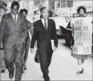  ?? ASSOCIATED PRESS FILE ?? In this Oct. 19, 1960, file photo, Dr. Martin Luther King Jr. under arrest by Atlanta Police Captain R.E. Little, left rear, passes through a picket line outside Rich’s Department Store, in atlanta. On King’s right are Atlanta Student Movement leader Lonnie King and Spelman College student Marilyn Pryce. Holding the sign is Spelman student activist Ida Rose Mccree. Following the publicatio­n of “An Appeal for Human Rights” on March 9, 1960, students at Atlanta’s historical­ly black colleges waged a nonviolent campaign of boycotts and sit-ins protesting segregatio­n at restaurant­s, theaters, parks and government buildings.