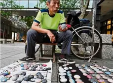  ??  ?? Wu rong-bi, also as know as ‘uncle Stone’, displaying colourfull­y painted stones along a street in Taipei.