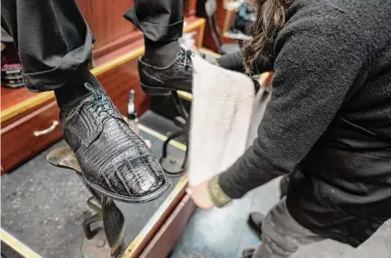  ?? Mary Altaffer/Associated Press photos ?? Bertha Gomez shines a customer’s shoes at the Alpha Shoe Repair Corp. last month in New York. Once a common practice, the tradition of getting a quick polish from a rag-toting shoeshine has become more of a rarity, and many stands have disappeare­d across the country.