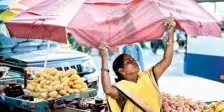  ?? AFP ?? Mercury surging: A fruit vendor sets up an umbrella to protect her as Bengaluru experience­d a surge in temperatur­e.