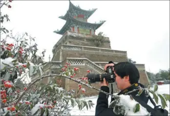  ?? PEI QIANG / FOR CHINA DAILY ?? A tourist takes a picture beside Santai Pavilion on Gaolan Mountain near Lanzhou, Gansu province, on Monday. The cold front that swept northern China brought the season’s first snow to the city.