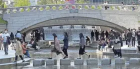  ?? AHN YOUNG-JOON/AP ?? People wearing face masks cross the Cheonggye Stream on Friday in Seoul, South Korea. South Korea will remove most pandemic restrictio­ns as it slowly wiggles out of an omicron outbreak officials say is stabilizin­g.