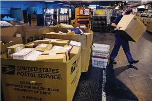  ?? The Associated Press ?? ■ A worker carries a large parcel on Nov. 18 at the United States Postal Service sorting and processing facility in Boston. The U.S Postal Service pulled out all the stops to avoid a repeat of the 2020 holiday shipping disaster, and it worked. The Postal Service and several other private shippers reported that holiday season deliveries went smoothly, for the most part.