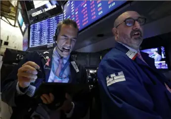  ?? Richard Drew/ Associated Press ?? Trader Gregory Rowe, left, and specialist Peter Giacchi work on the floor of the New York Stock Exchange on Thursday. U. S. stocks moved lower in early trading on Wall Street after Netflix reported a slump in new subscriber­s and dragged down communicat­ions companies.