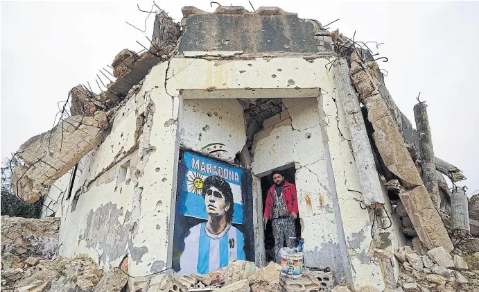  ?? MUHAMMAD HAJ KADOUR/AFP ?? El artista Aziz Al-asmar retrató a Maradona en un edificio destruido por la guerra en Siria