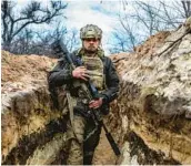  ?? JOHN MOORE/GETTY ?? A Ukrainian sniper moves to a fighting position in a front-line trench facing Russian troops Sunday outside Bakhmut, a beset city in the Donetsk province.