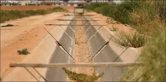  ?? MATT YORK / AP (2022) ?? A dry irrigation canal runs between two unplanted fields as new home constructi­on abuts dormant fields in Maricopa, Ariz.