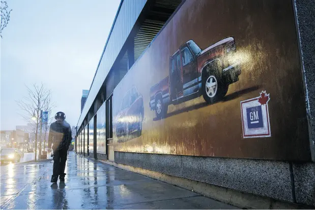  ?? COLE BURSTON / BLOOMBERG NEWS ?? A pedestrian walks past a General Motors Co. mural in downtown Oshawa, Ont. After churning out vehicles for General Motors for more than a century, the city east of Toronto could find itself without a plant as the Detroit-based automaker extends its shift into electric vehicles.