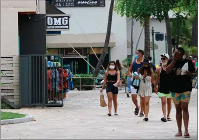  ?? (AP) ?? People walk past restaurant­s and shops in Honolulu last week. The Conference Board said Tuesday that the surge of covid-19 has dented consumers’ views of the economy.