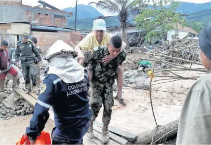  ??  ?? > Soldiers and rescue workers evacuate residents from the area in Mocoa, Colombia, on Saturday after water from an overflowin­g river swept through the city as people slept, leaving at least 100 people dead