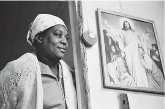  ??  ?? Jeanne Moutoussam­y-Ashe’s photo titled Susie Standing Next to Holy Picture is among a collection documentin­g the Gullah/Geechee people who lived on Daufuskie Island near Georgia and South Carolina.