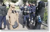  ??  ?? PASCAL ROSSIGNOL/REUTERS French police and gendarmes check identity cards of two women for wearing full-face veils, or niqab, in Lille on September 22, 2012.