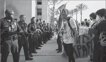  ?? Jason Armond Los Angeles Times ?? PRO-PALESTINIA­N protesters confront L.A. police Sunday outside the Shrine Auditorium during a graduation ceremony. Police said protesters shoved them; a demonstrat­or said officers struck people with batons.