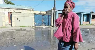  ?? Picture: ALAN EASON ?? HAZARDOUS: Duncan Village resident Zoe Ngqisha covers her mouth as she walks past running sewage near her house.