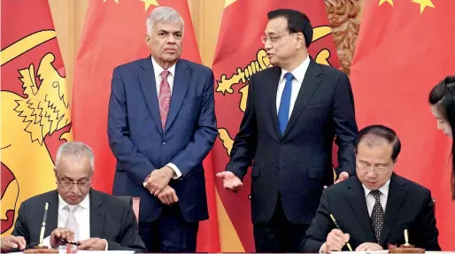  ??  ?? Prime Minister Ranil Wickremesi­nghe speaks to Chinese Premier Li Keqiang (back R) as Internatio­nal Trade and Strategic Developmen­t Minister Malik Samarawick­reme and his Chinese counterpar­t sign the agreement at the Great Hall of the People in Beijing...