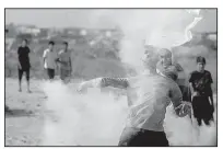  ?? AP/KHALIL HAMRA ?? A Palestinia­n protester on Friday throws back a tear gas canister fired by Israeli soldiers during clashes on the Israeli border with Gaza related to protests against metal detectors Israel installed at a shrine in Jerusalem.